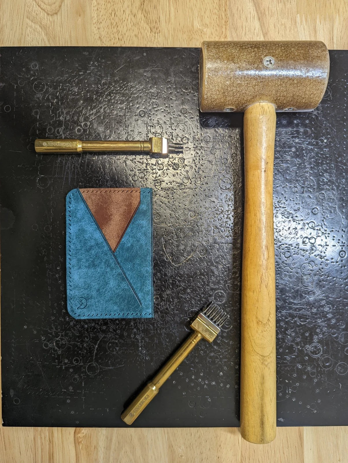 Leather wallet panel on the workbench beside edge and leatherworking tools